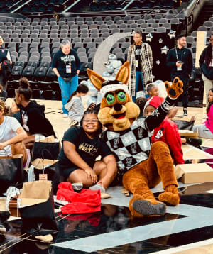 The San Antonio Spurs' Coyote poses for a photo with one of the girls from S.J. Davis Middle School following the team's gift-opening at Frost Bank Center.